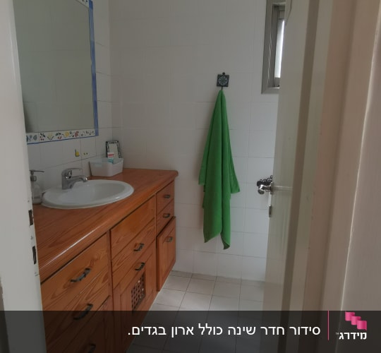 חדר אמבטיה עם ארון עץ, כיור ומגבת ירוקה